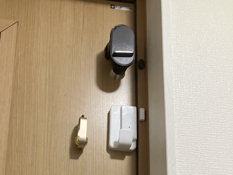 高所のQrio Lockの下に付いている金色の鈴と白い開閉センサー